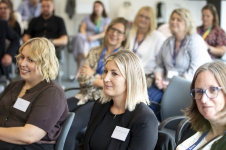 A group of women sitting in an audience looking ahead.